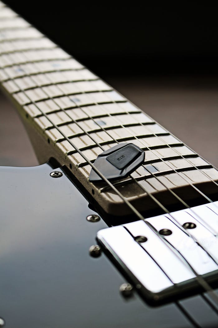 Detailed shot of an electric guitar showcasing strings and metallic frets on the fingerboard.